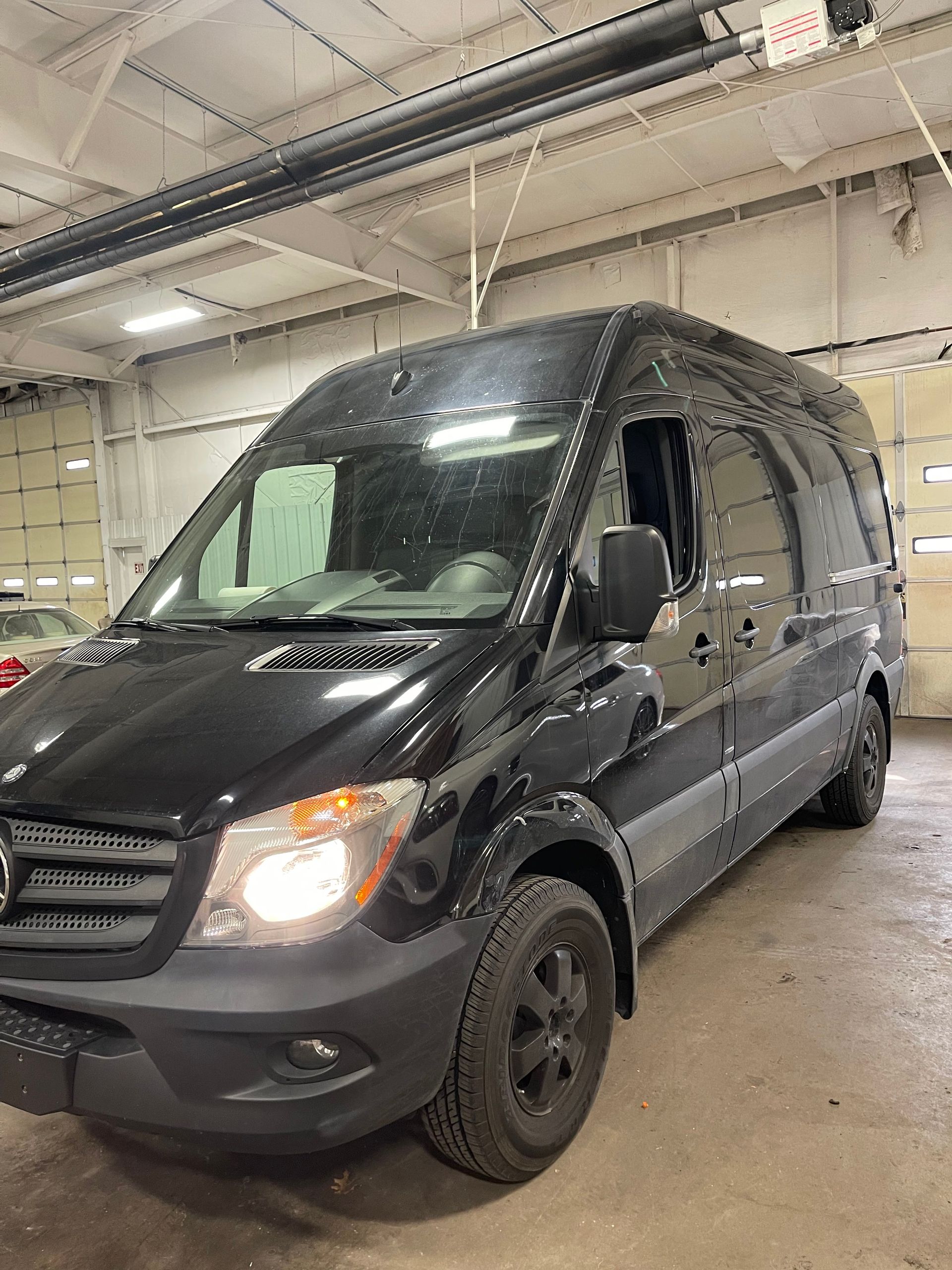 Black Mercedes-Benz Sprinter van in an indoor garage with bright lighting. | Benz Tech