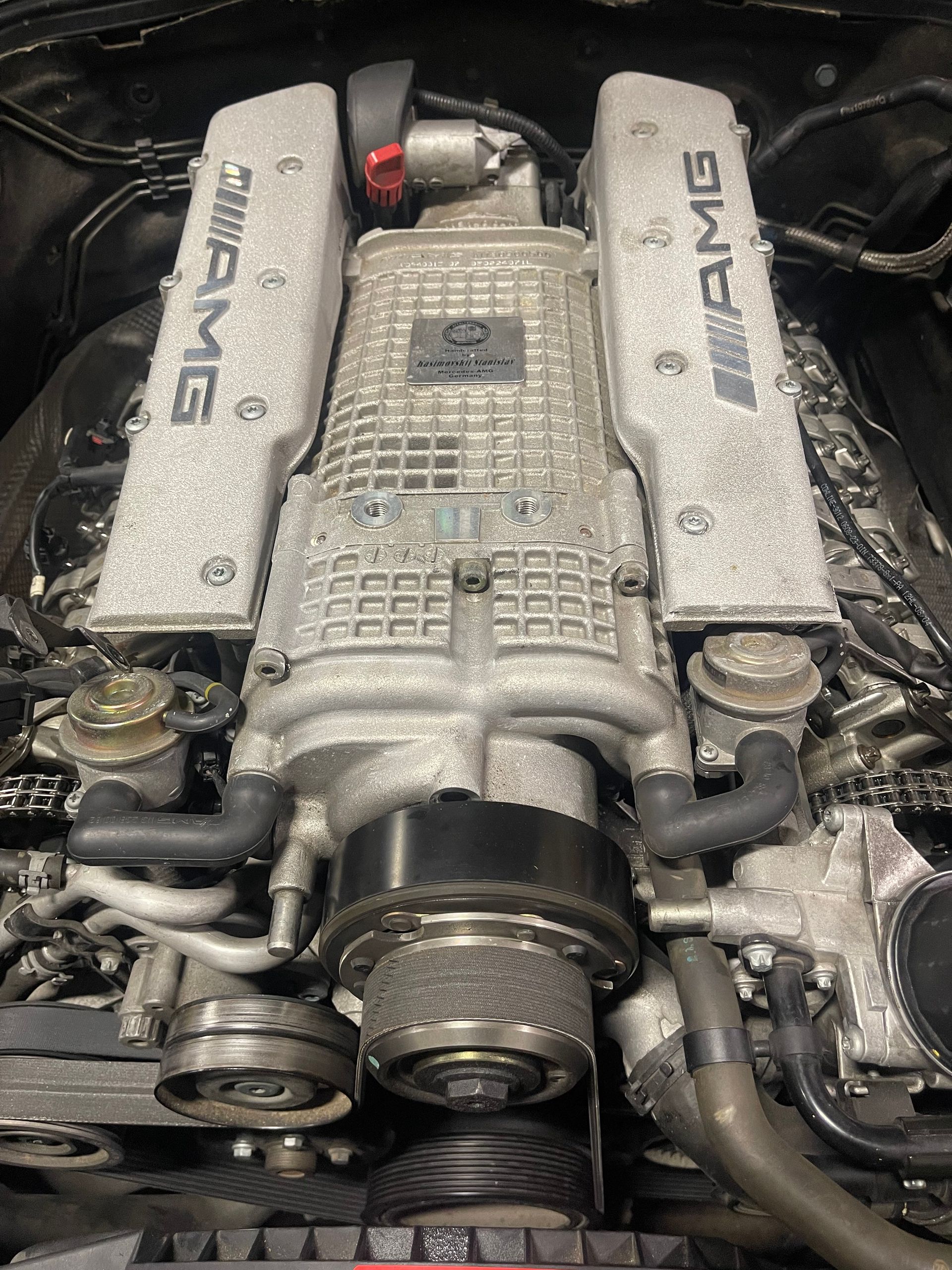 Mercedes-Benz AMG supercharged engine, gray metallic finish, belts, and pulleys visible. | Benz Tech