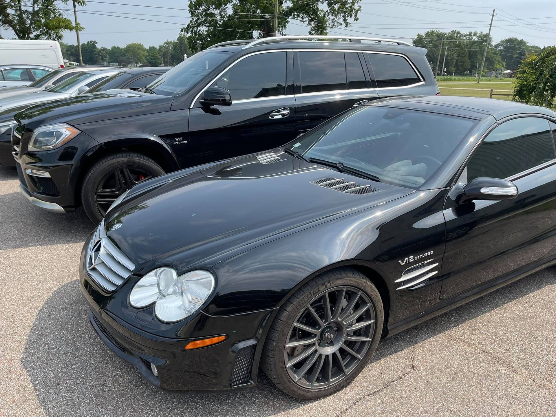 Black Mercedes-Benz SL and SUV parked outside on a sunny day. | Benz Tech