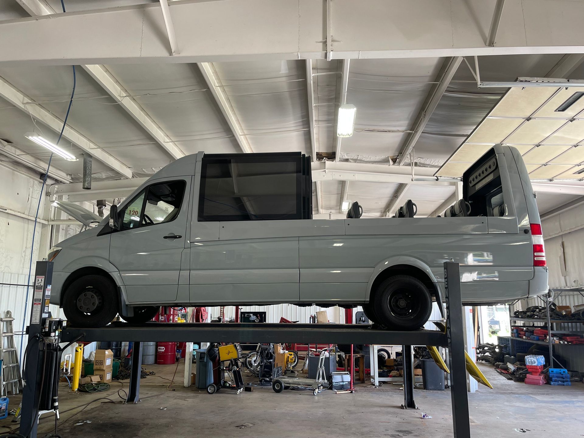Gray custom Sprinter van conversion on a car lift in a garage. | Benz Tech