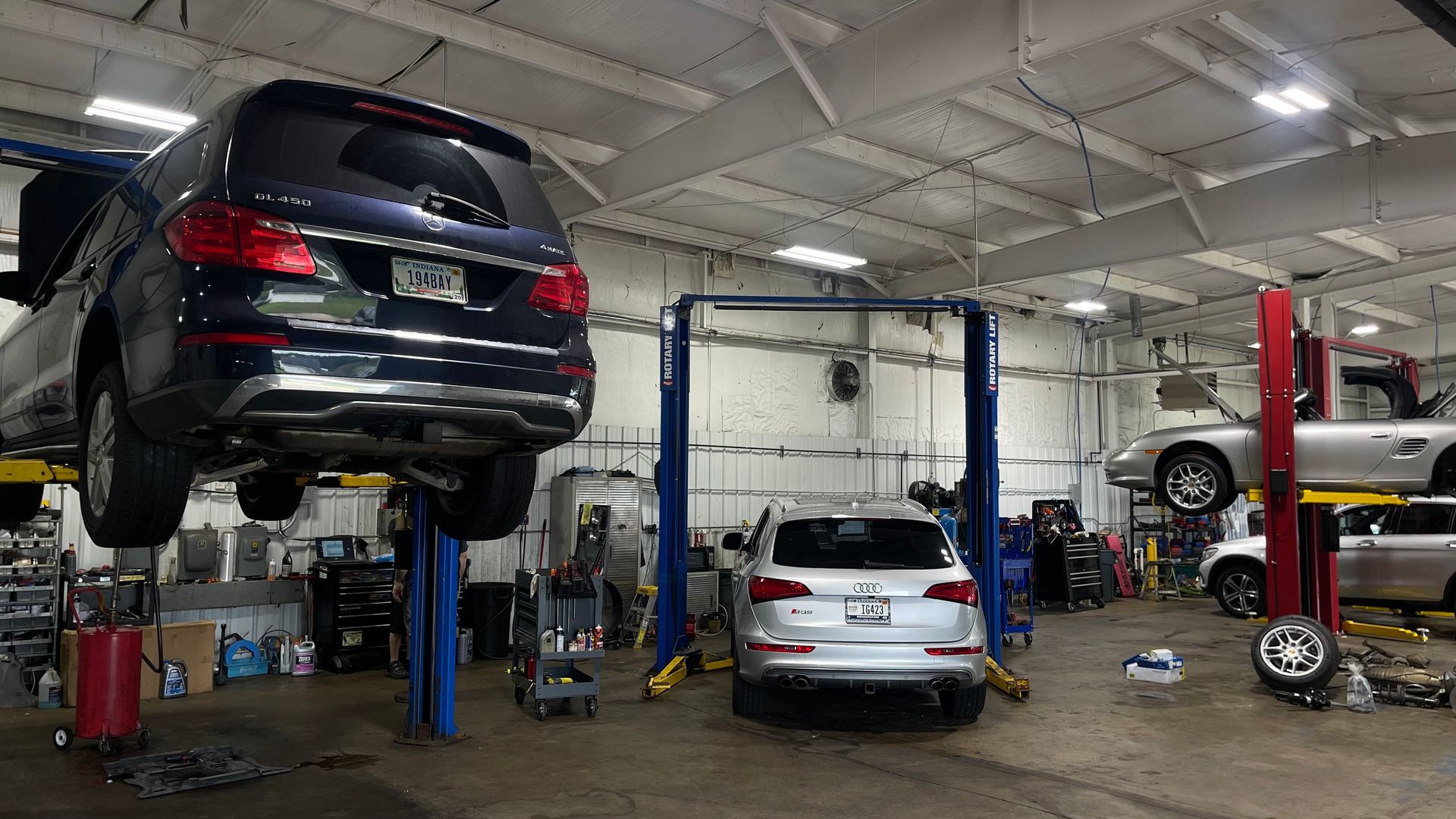 A car repair shop with three cars on lifts. An SUV is being worked on. | Benz Tech