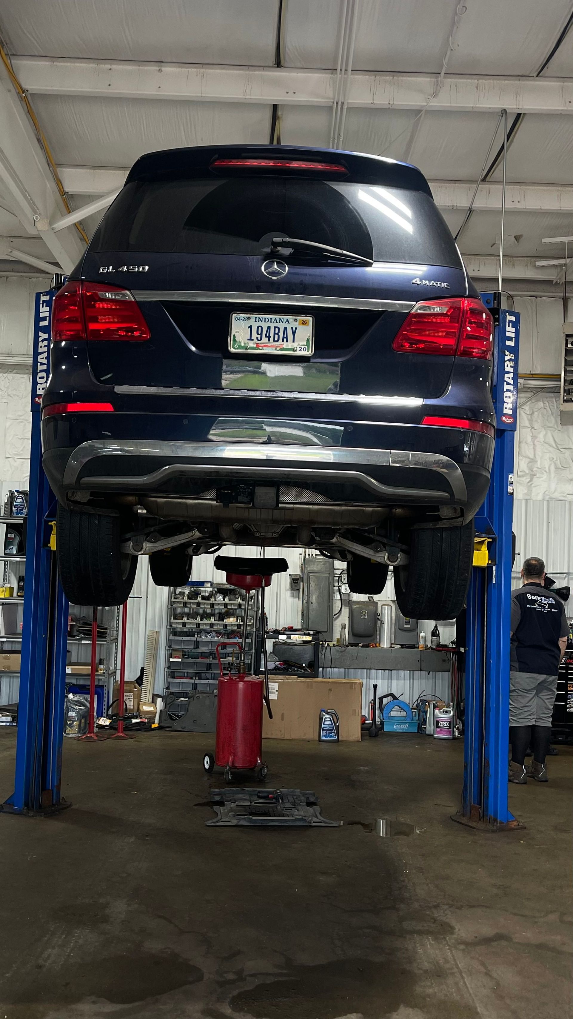 Blue SUV elevated on a car lift in a mechanic's garage, preparing for service. | Benz Tech