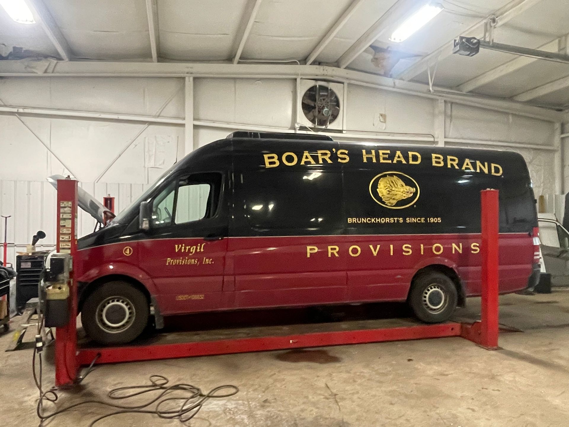 Boar's Head Brand Provisions van on a red lift in a garage. Black and red exterior. | Benz Tech