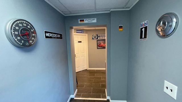 Hallway with gray walls decorated with automotive-themed decor and a doorway leading further in. | Benz Tech