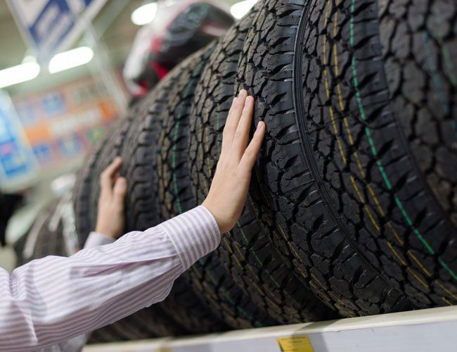 A person is touching a tire in a store.