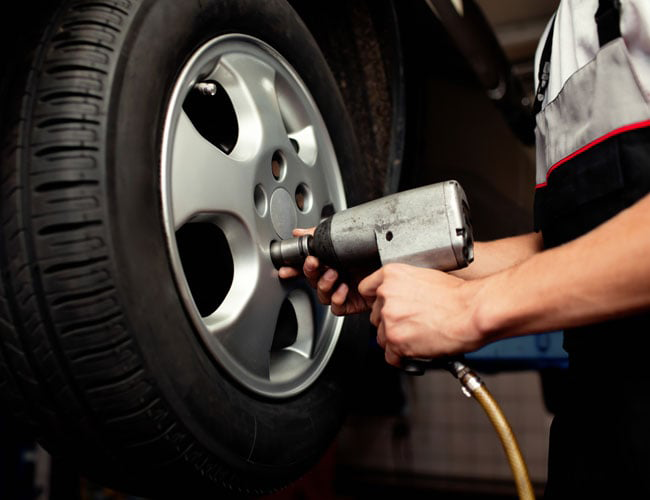 A person is touching a tire in a store.