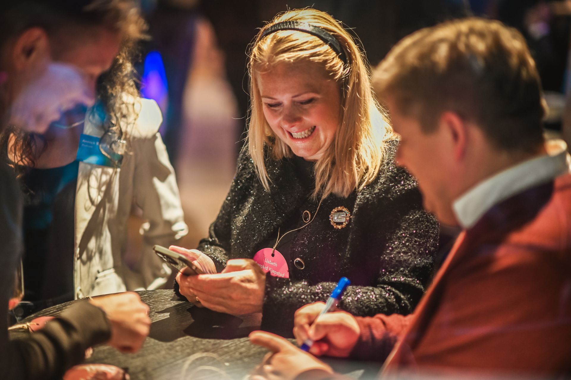 People gather around a table, collaborating and writing in a rustic room.