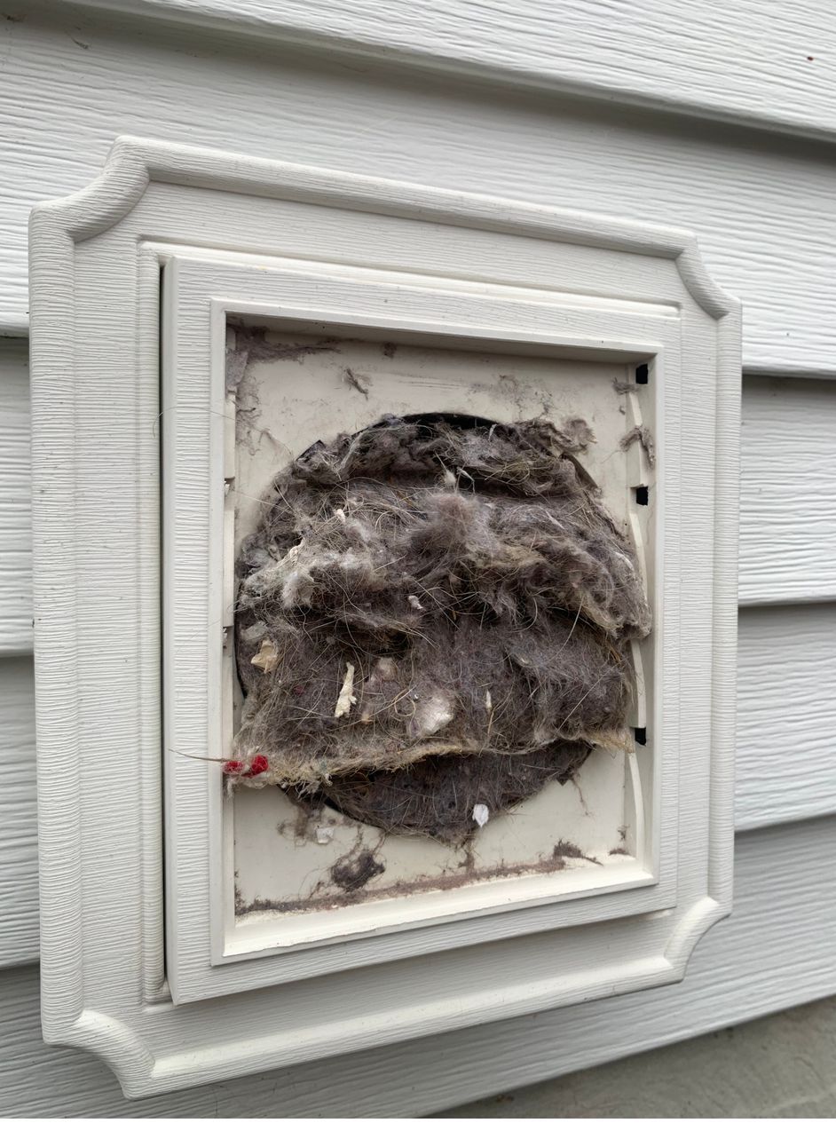 A picture of a dirty vent on the side of a house.