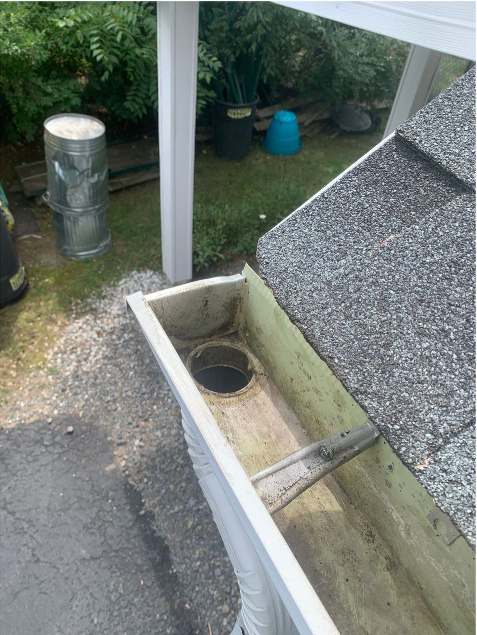 A gutter with a hole in it is sitting on top of a roof.