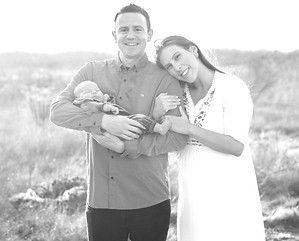 A man and a woman are holding a baby in a black and white photo.