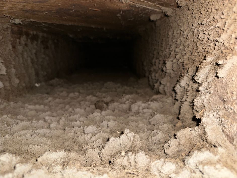 A dirty duct with a lot of dust coming out of it.