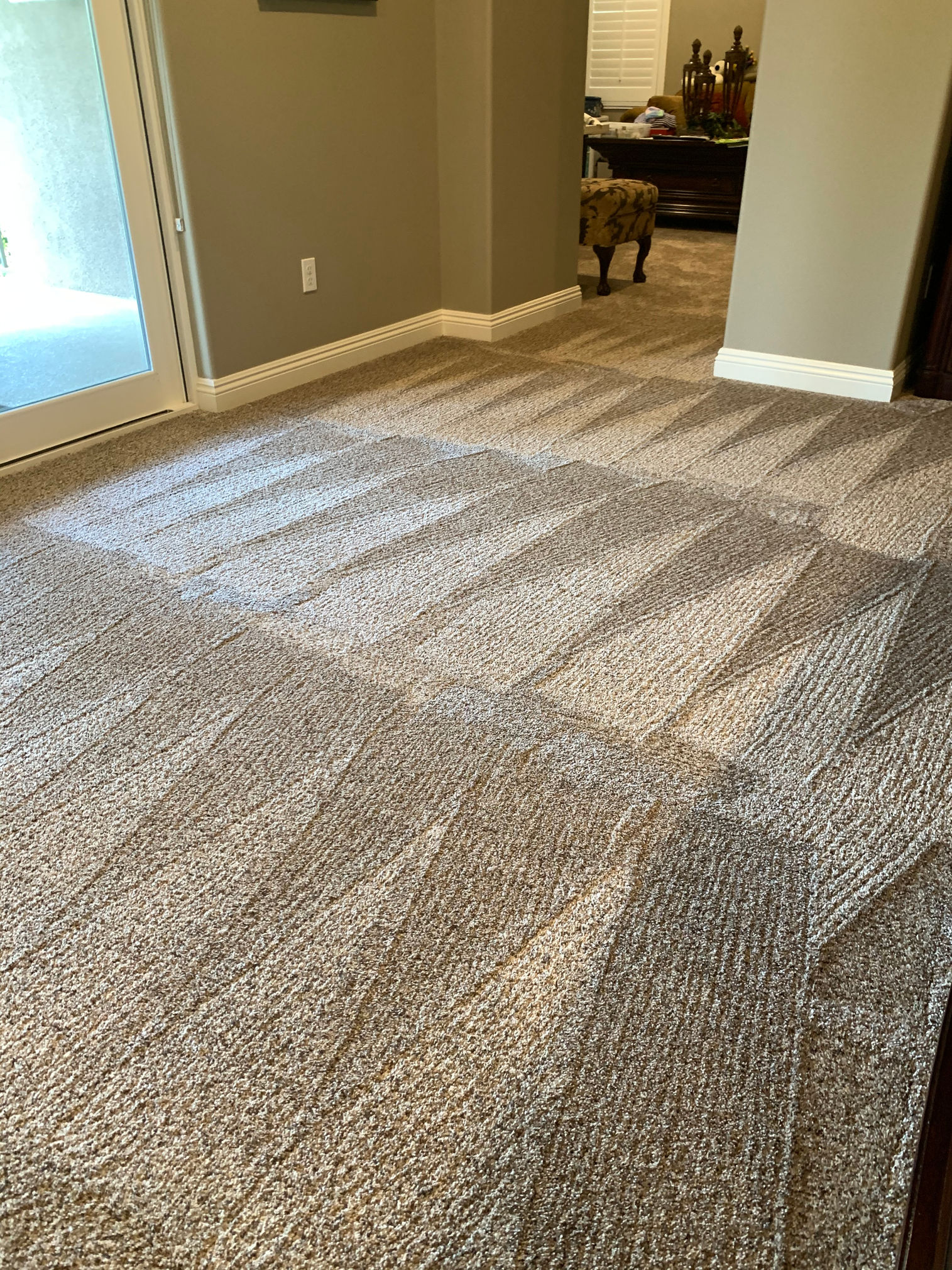 A living room with a carpeted floor and a sliding glass door.