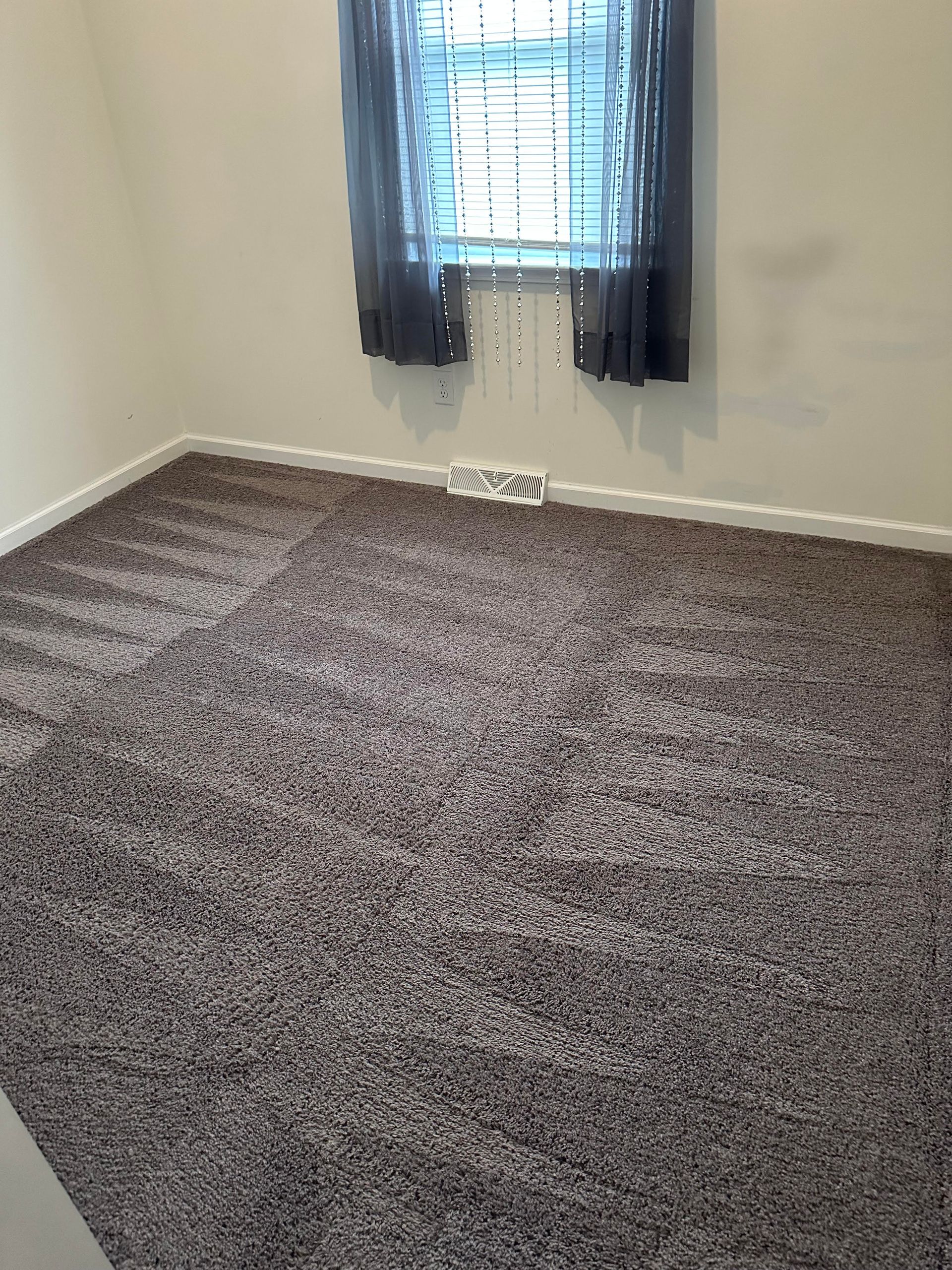 An empty room with a carpeted floor and a window.