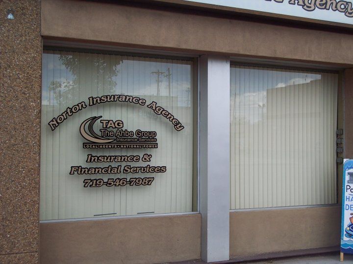 Exterior of the Norton Insurance Agency with text on the window and vertical blinds.