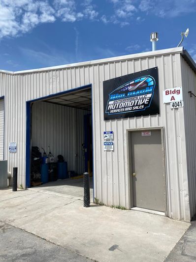 A white building with a blue door and a sign on the side.