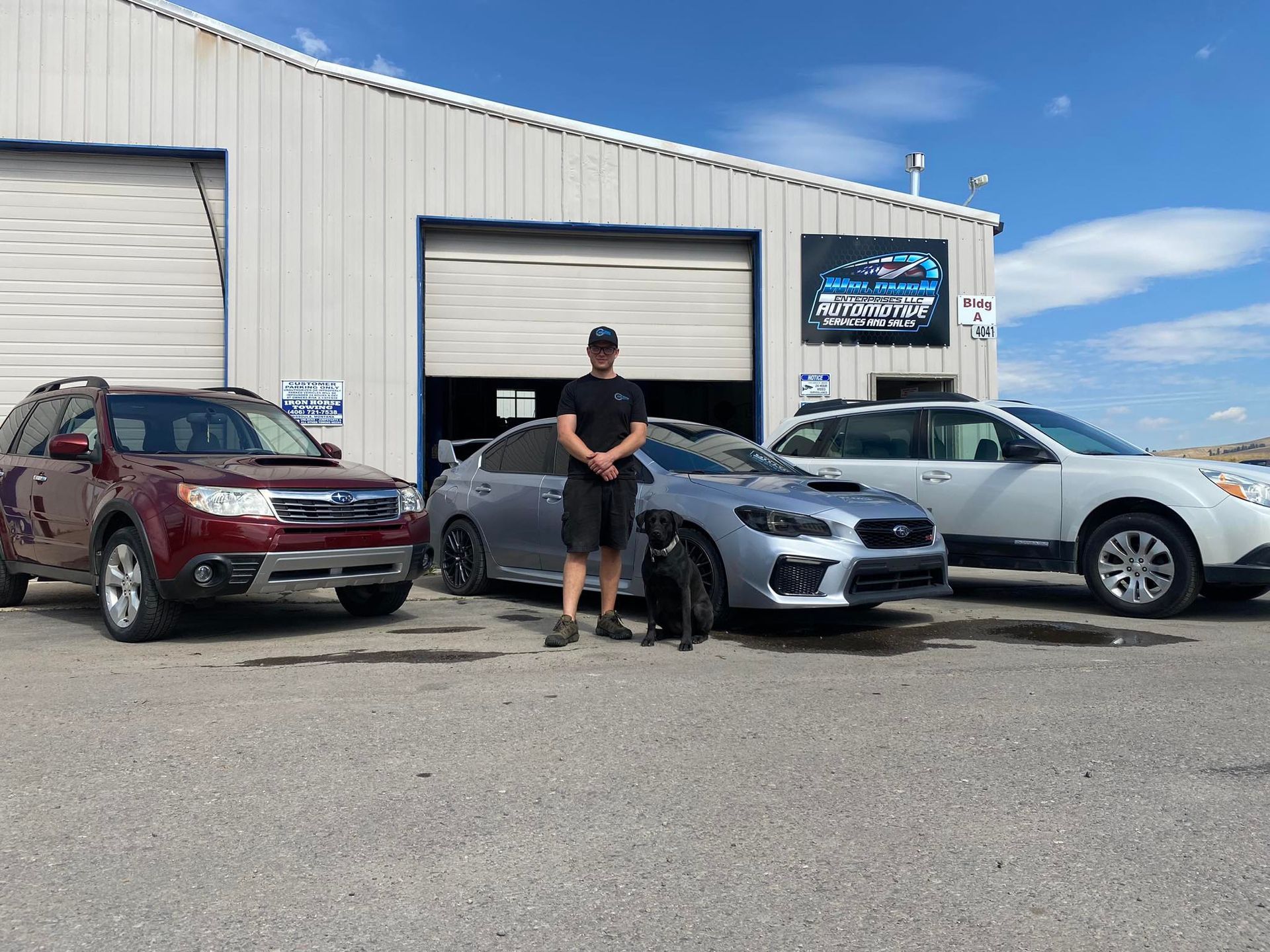 A man is standing in front of three cars in a parking lot.