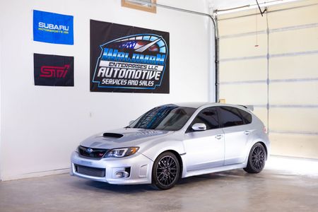 A silver subaru wrx sti is parked in a garage.