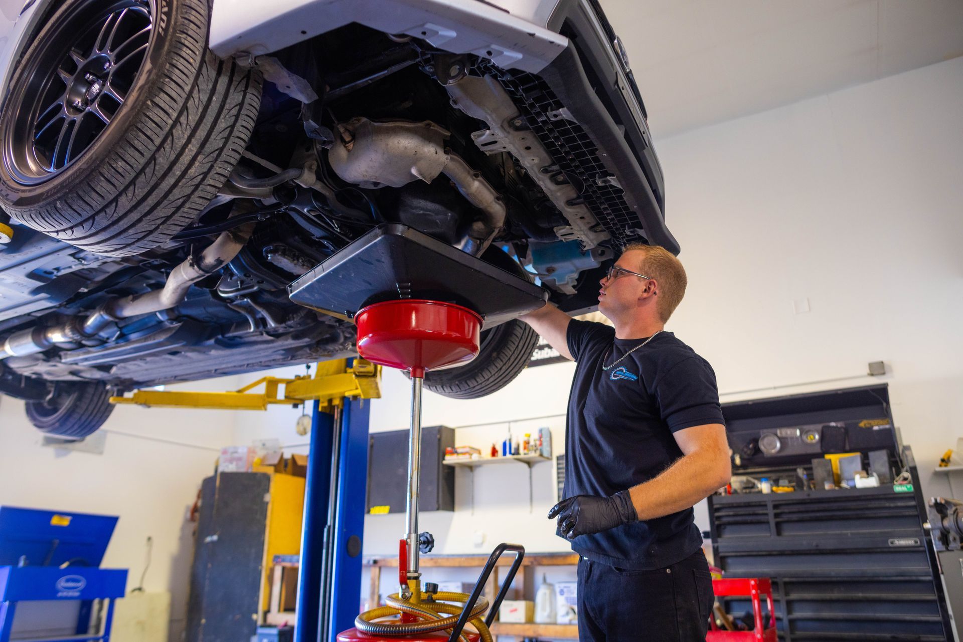 A man is working under a car on a lift in a garage.