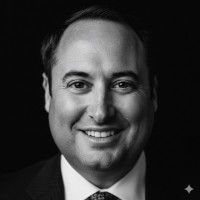 Man in a suit smiles at the camera, black and white portrait.