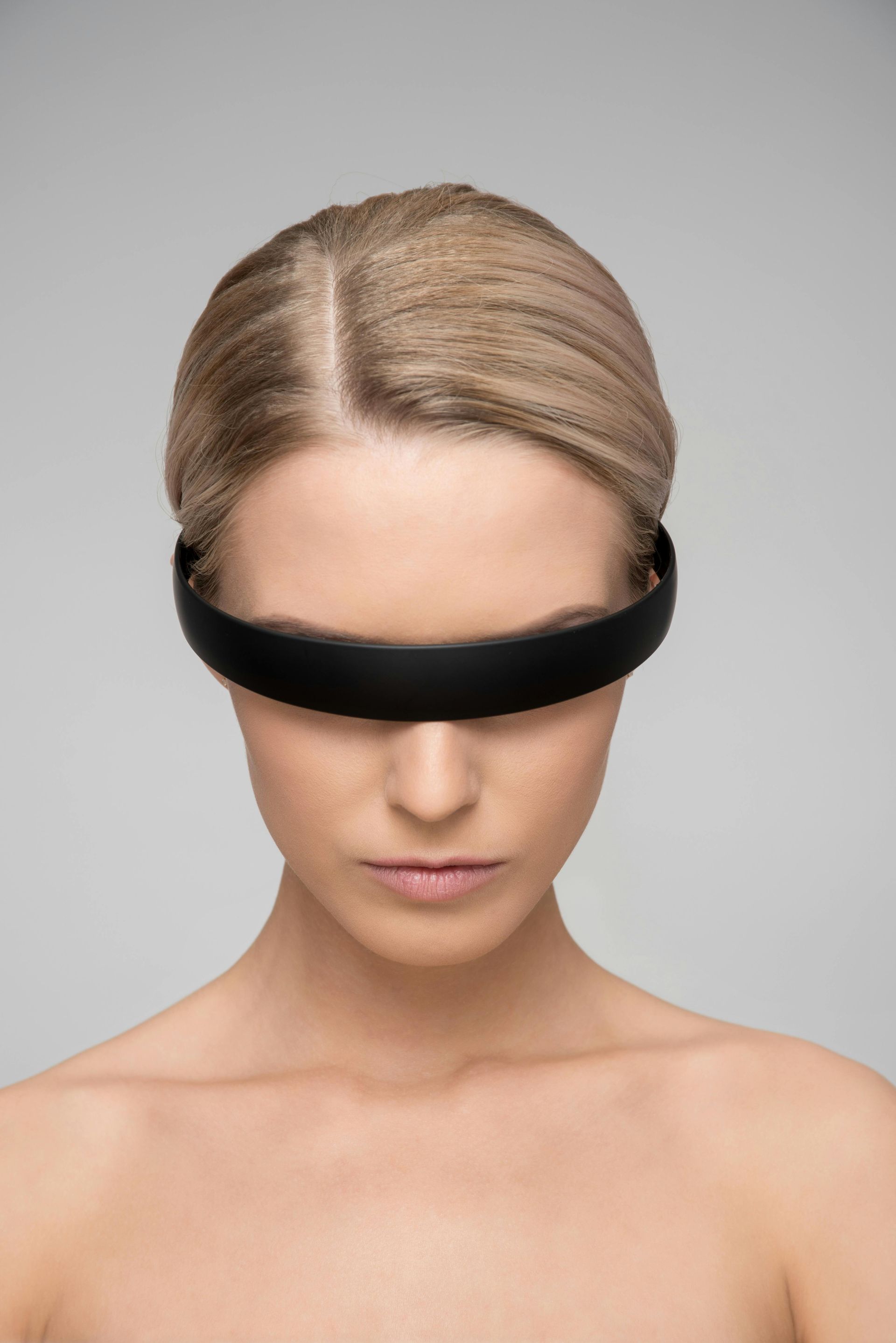 A woman is wearing a black headband over her eyes.