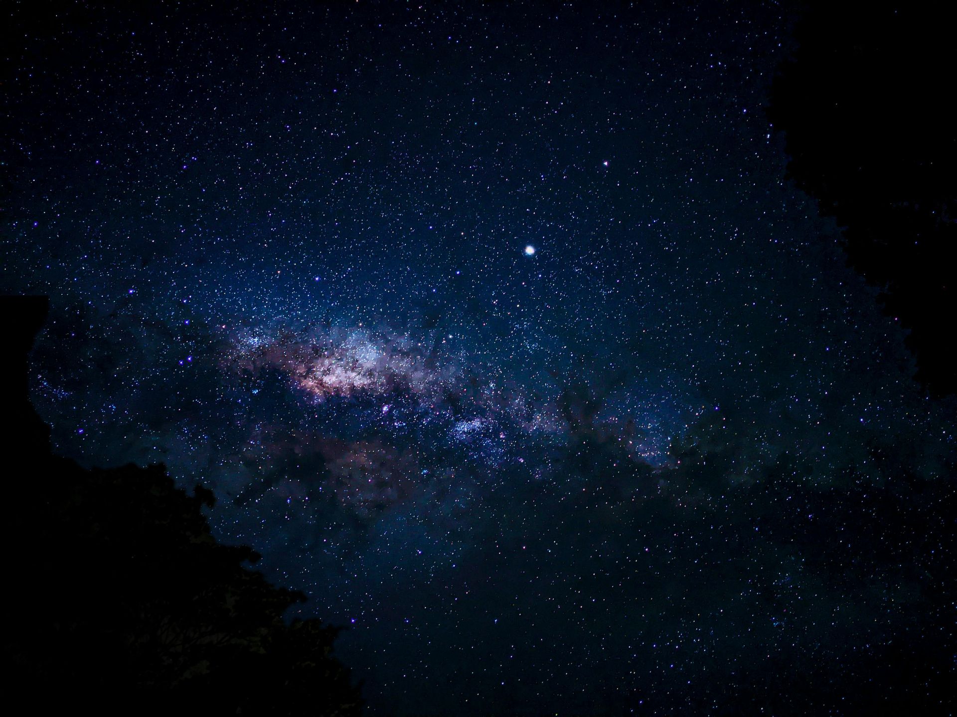 The starry night sky showing the bright, glowing band of the Milky Way galaxy against a deep blue and black backdrop.
