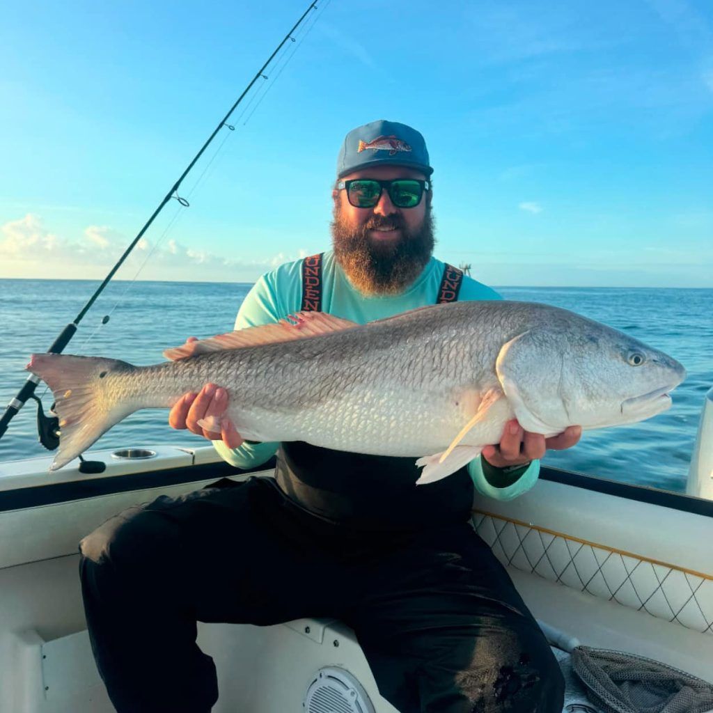 A man is sitting on a boat holding a large fish.