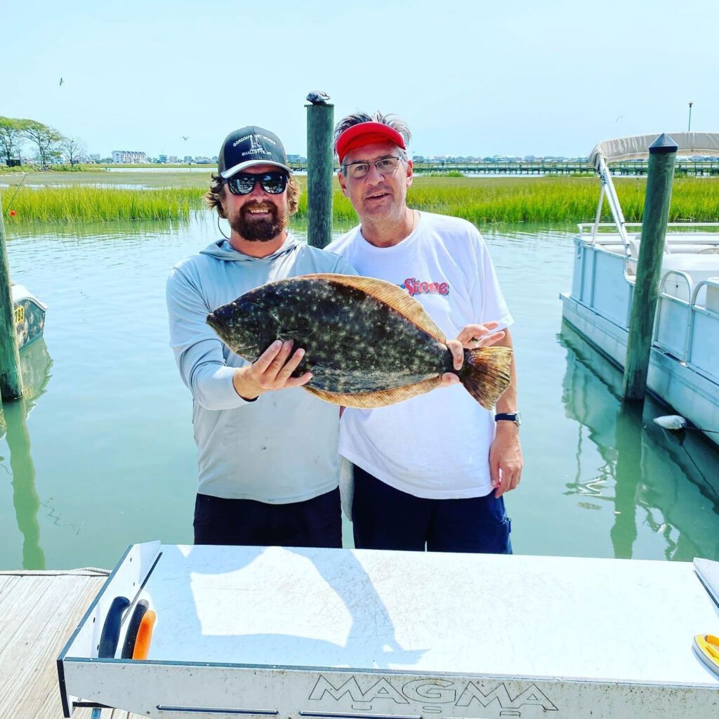 Two men standing next to each other holding a large fish