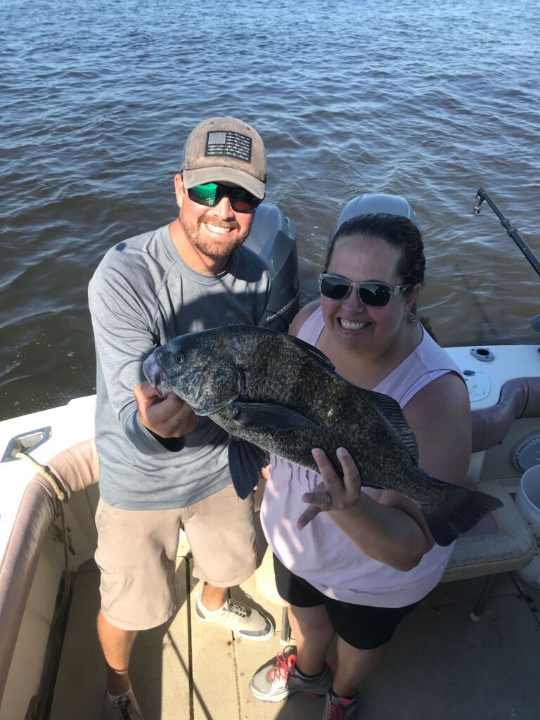 A man and a woman are holding a large fish on a boat.
