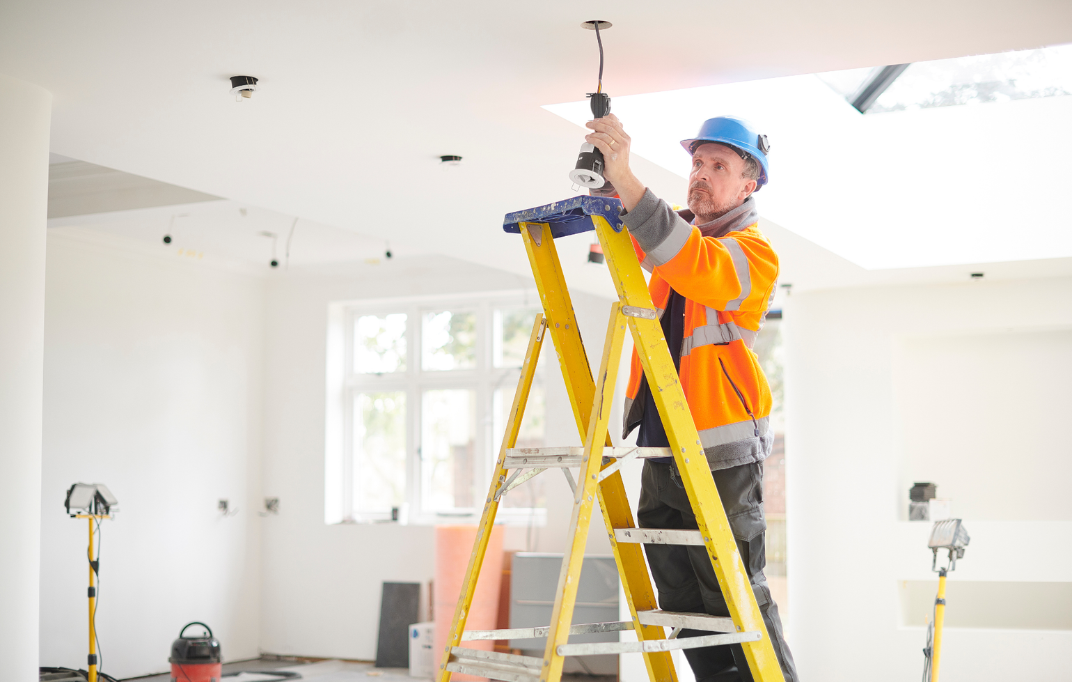 An electrician is working on an electrical panel with a screwdriver.