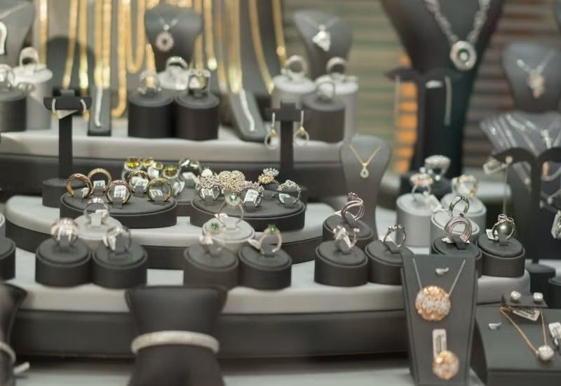 Jewelry display case with rings, necklaces, and bracelets on black stands in a store