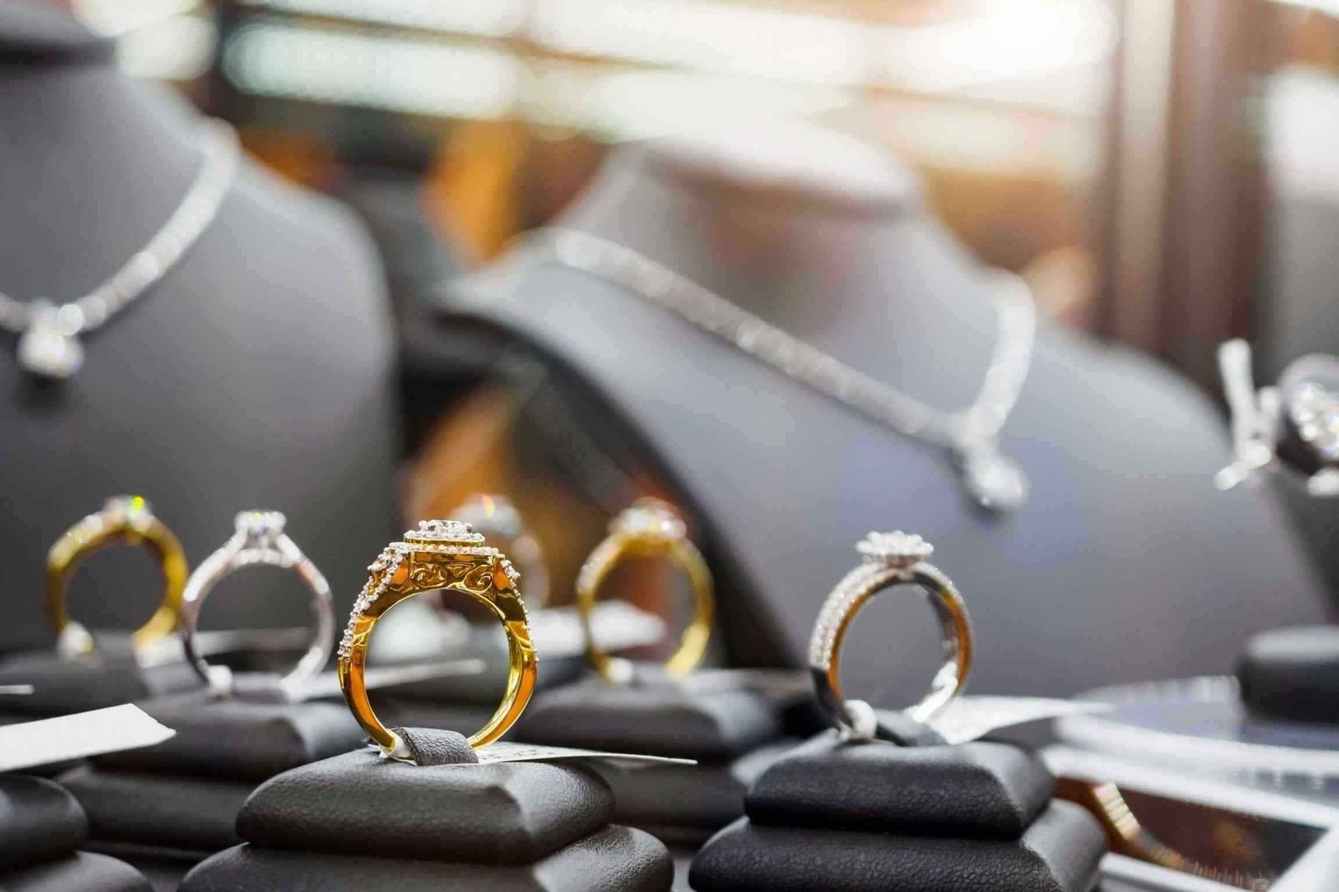 Display of gold and silver rings on black velvet stands in a jewelry store showcase
