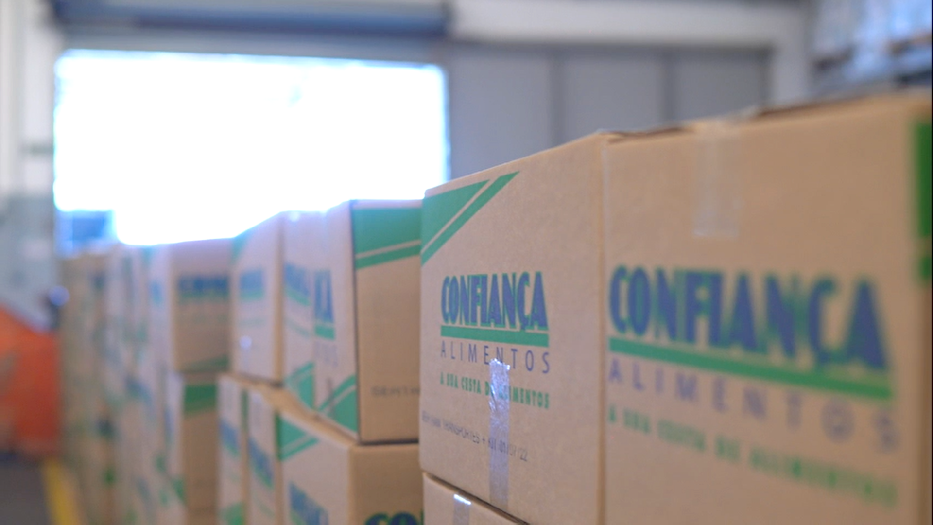 Uma fileira de caixas de papelão empilhadas umas sobre as outras em um armazém.