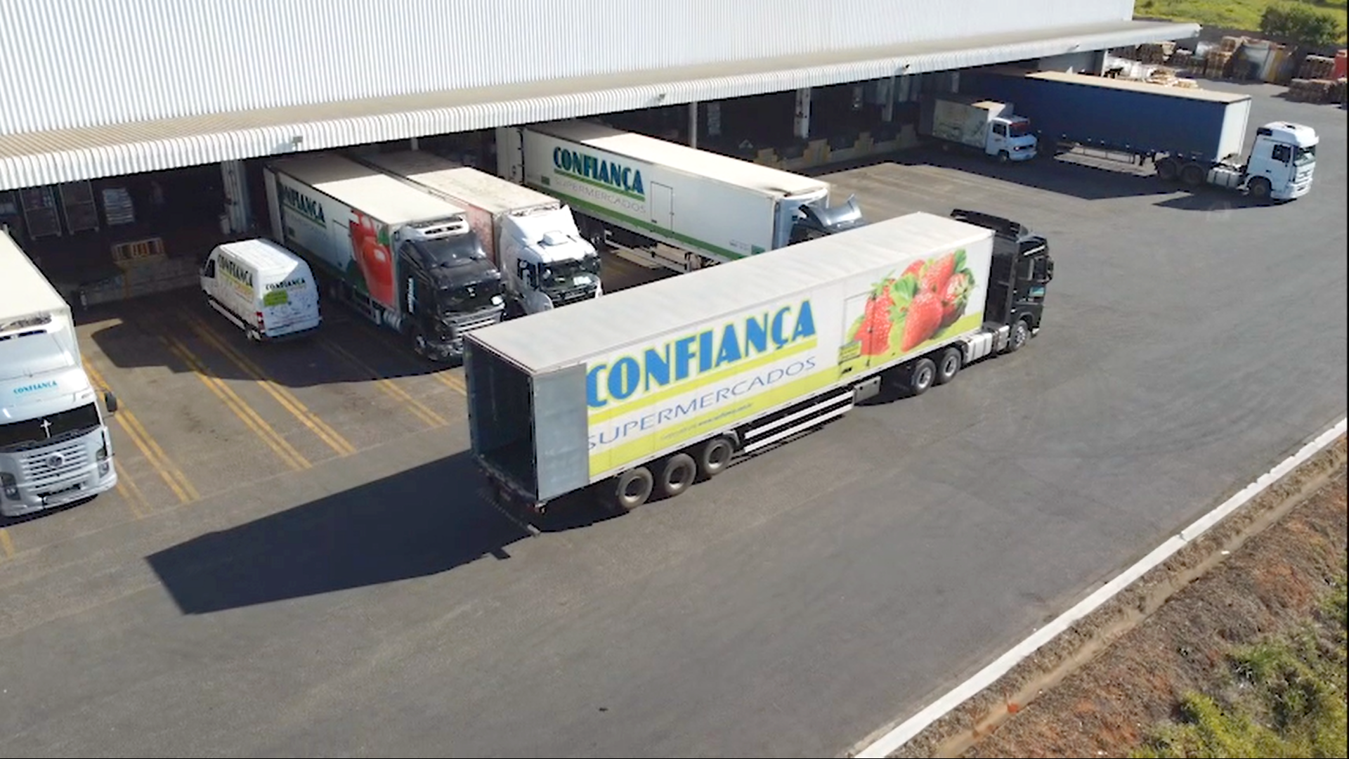 Uma vista aérea de um armazém com caminhões estacionados em frente.