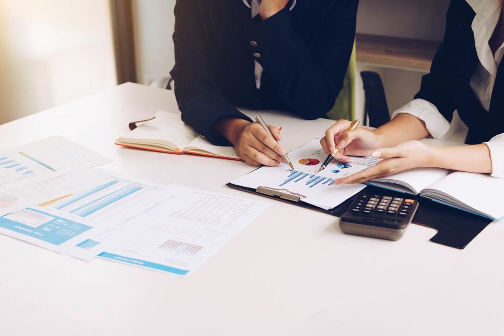 A Two People Reviewing Financial Documents at a White Desk — Tenth Avenue Accountants & Financial Advisors in Toukley, NSW