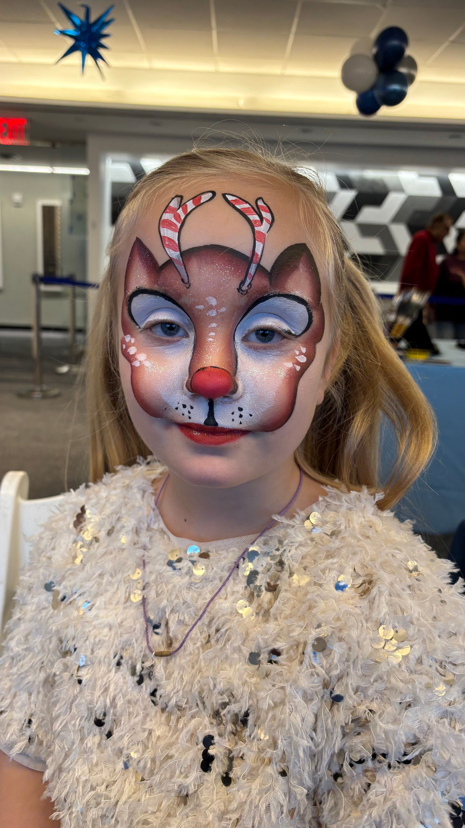 Girl wearing white with a painted face of a reindeer