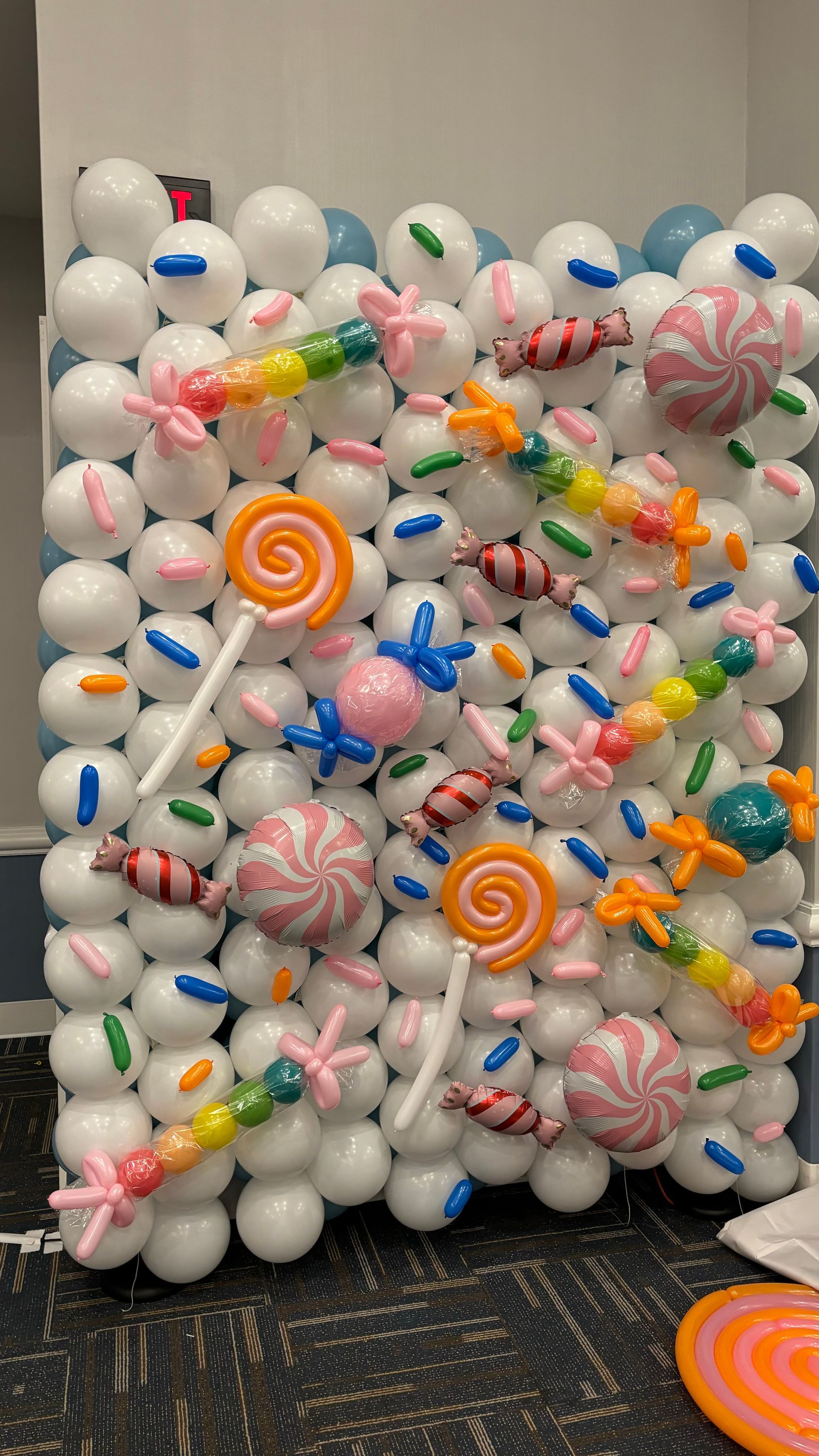 A candy-themed balloon wall with white and pastel decorations.