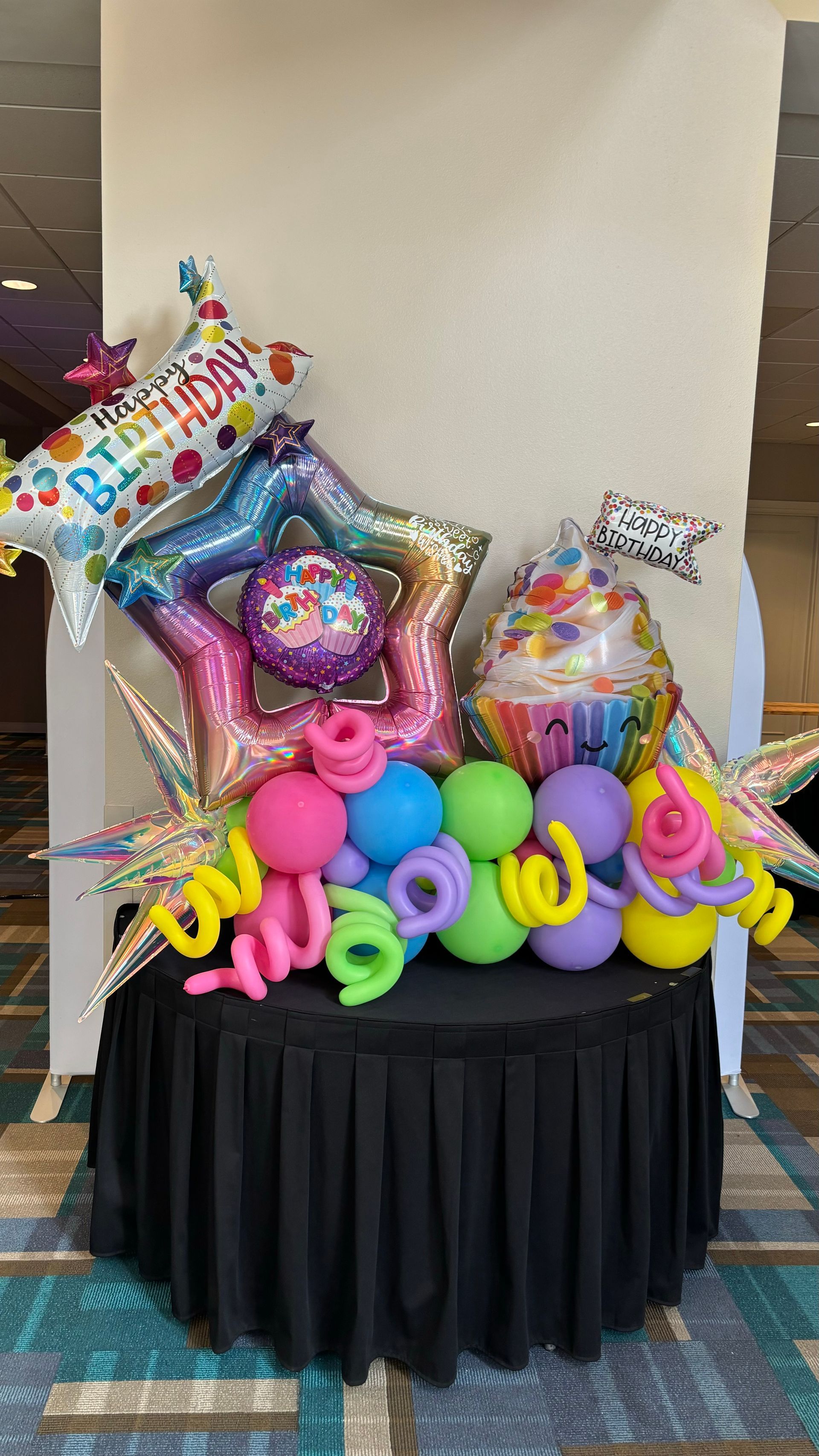 A table with a happy birthday balloons bouquet on it.