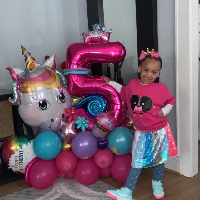 Girl poses next to a unicorn and 