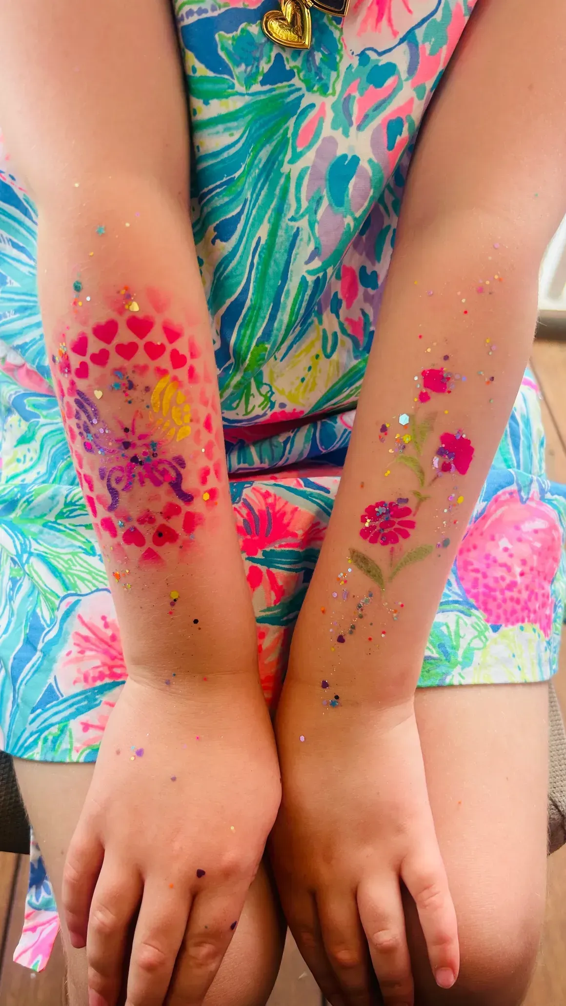 A little girl with flowers painted on her arms.