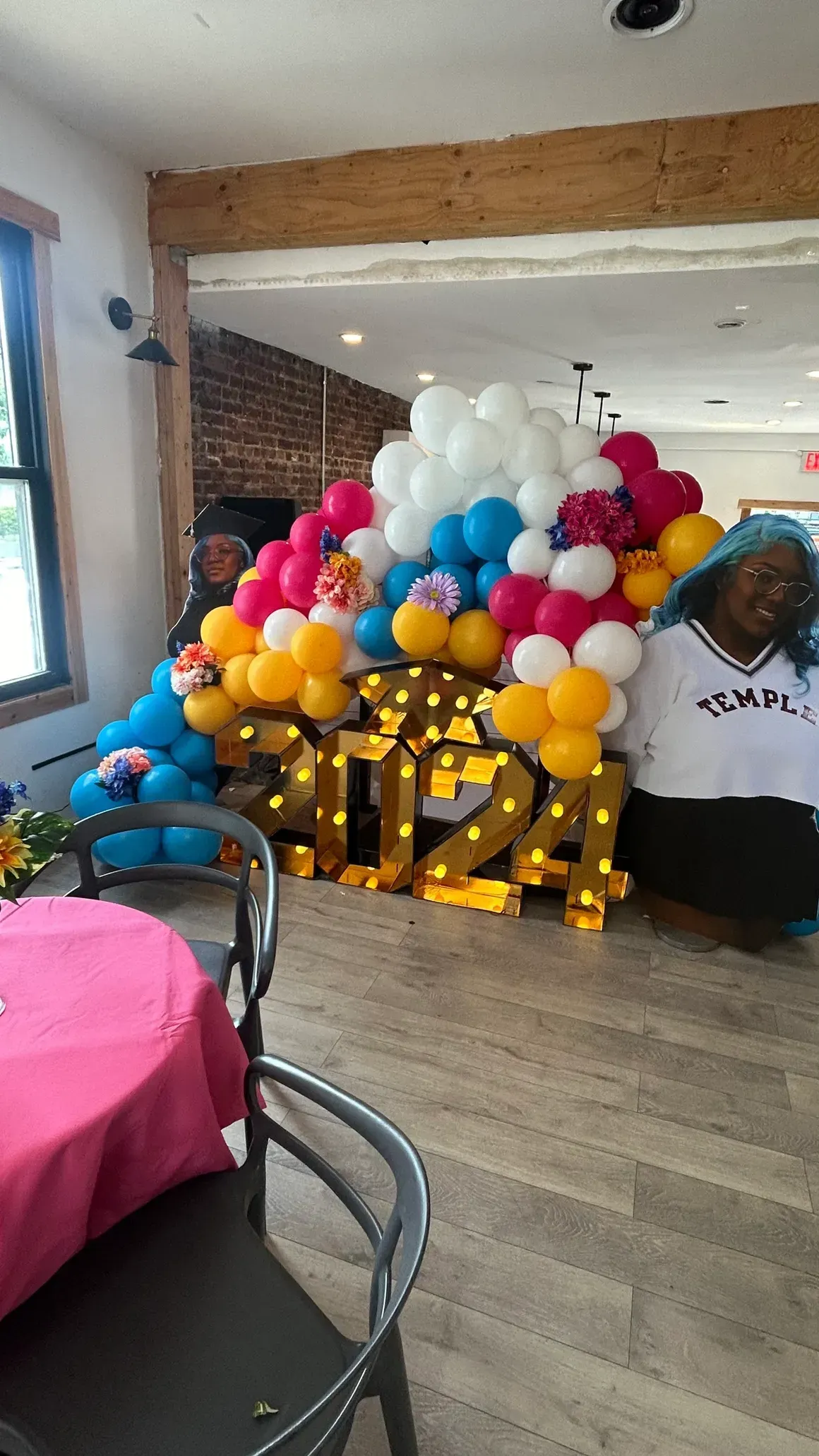 A room filled with balloons and a table with a pink tablecloth.