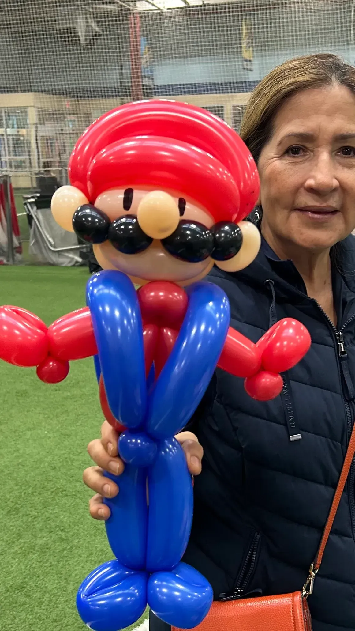 A woman is holding a mario made out of balloons.