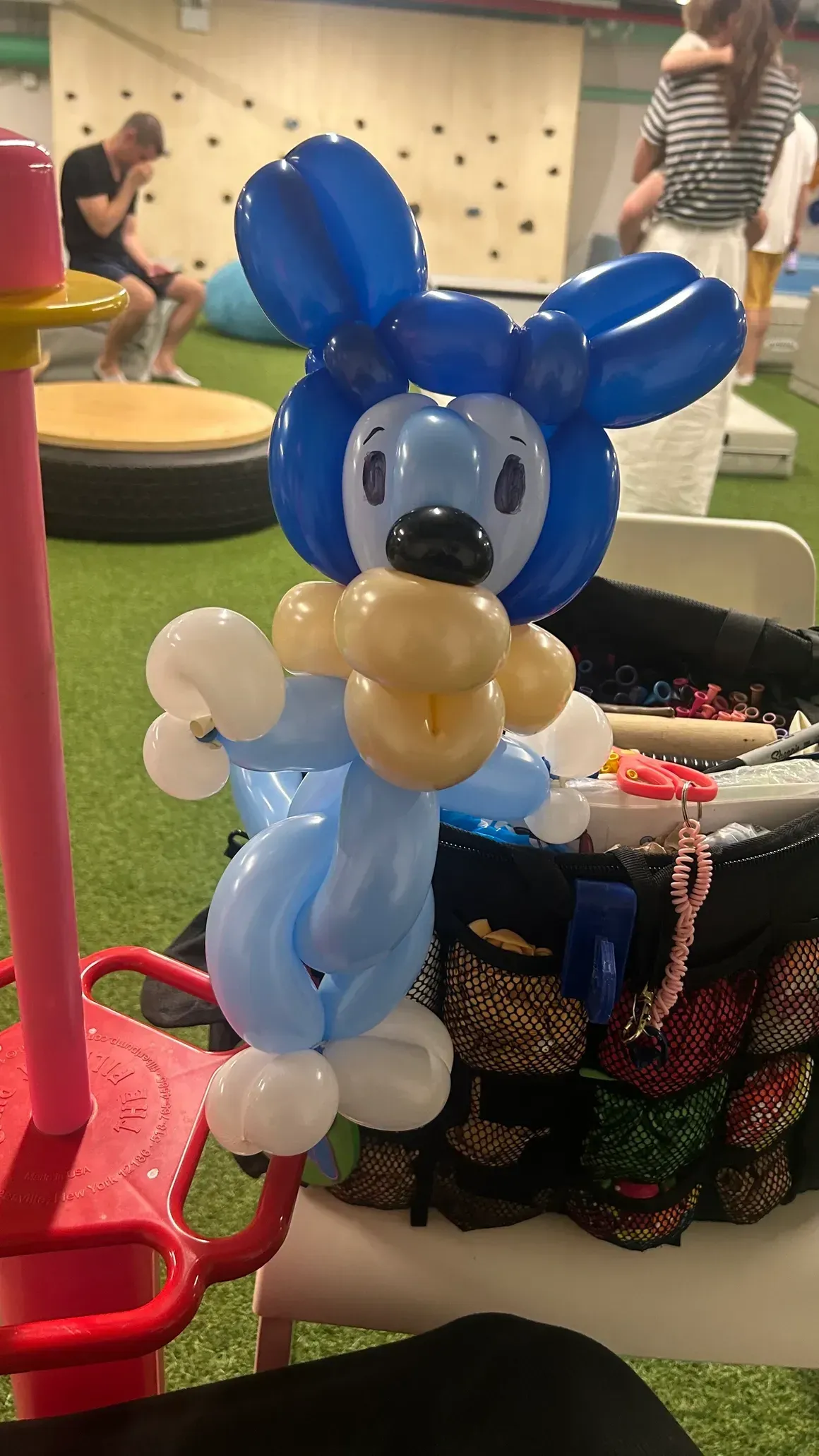Blue and white balloon seal sculpture standing; indoors, possibly a children's play area.