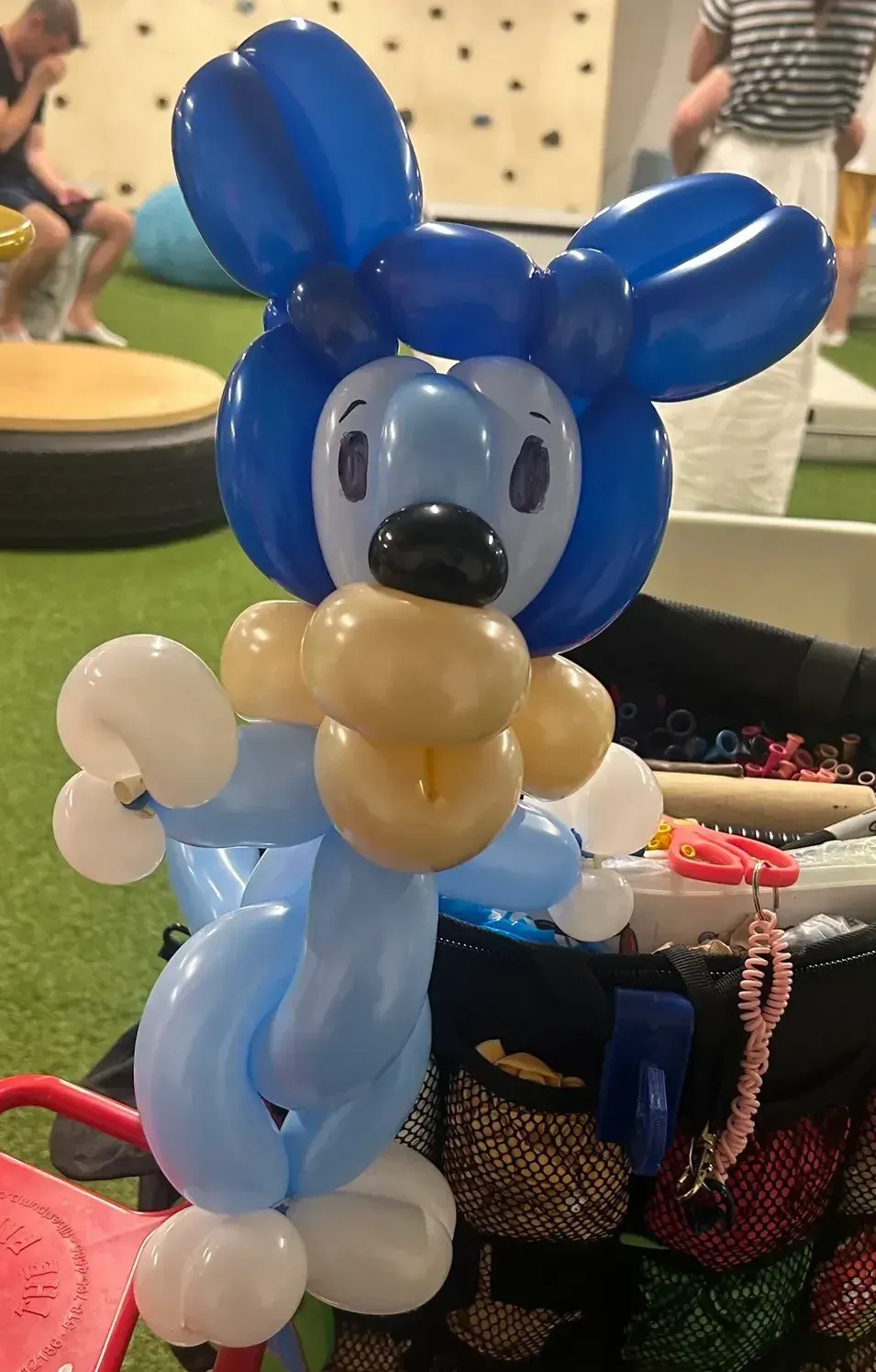 Blue and tan balloon animal dog, with large ears, standing on a table.