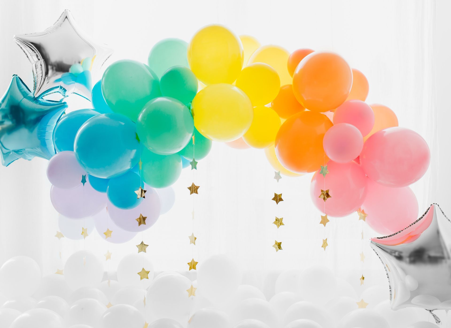 Rainbow balloon arch with silver star balloons and gold star confetti.