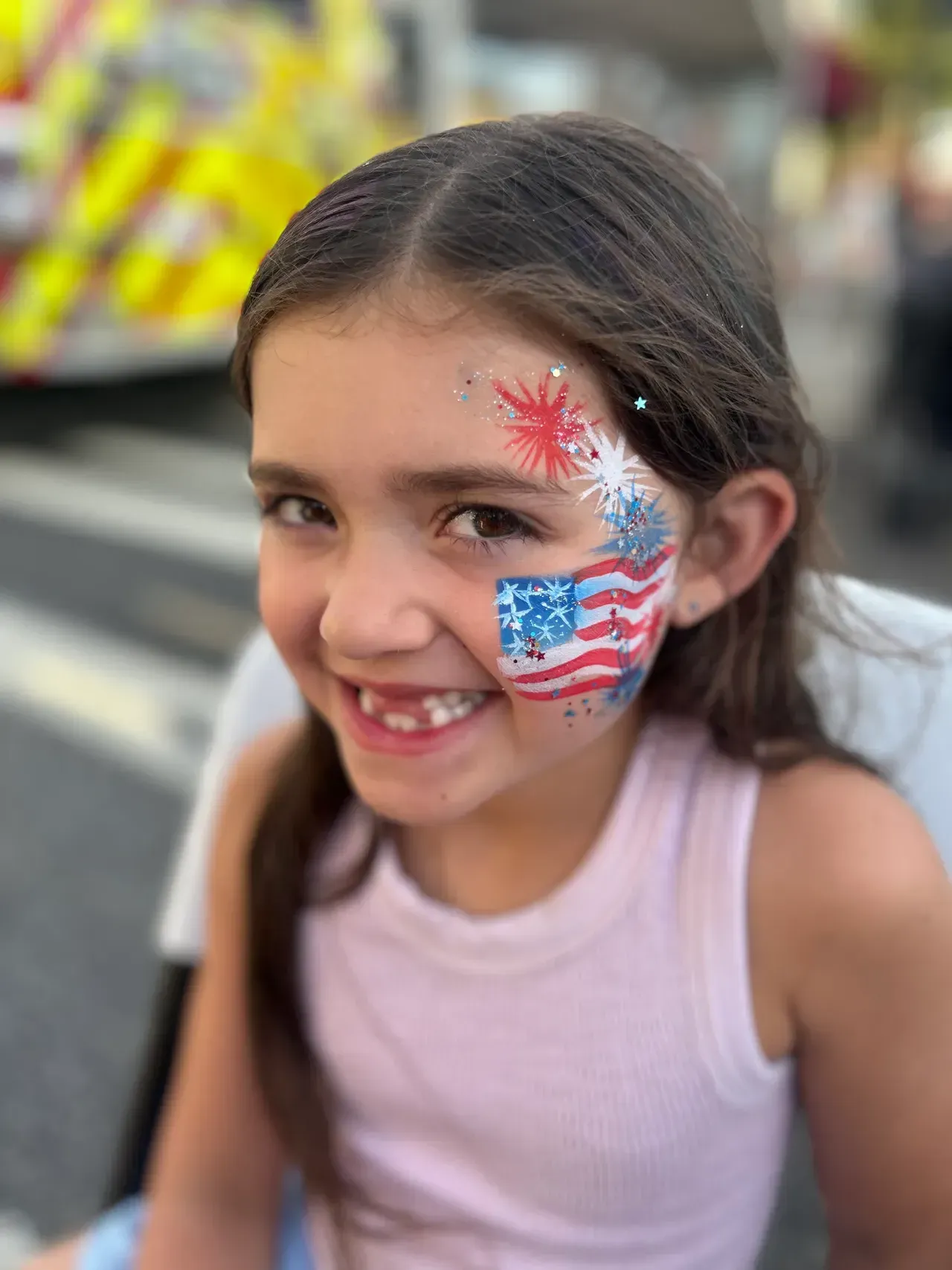 A little girl with an american flag painted on her face.