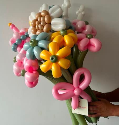 A person is holding a bouquet of flowers made out of balloons