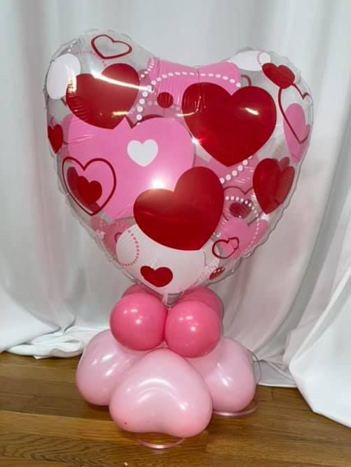Valentine's Day heart-shaped balloon display. Pink and red heart balloons arranged on a wooden floor.