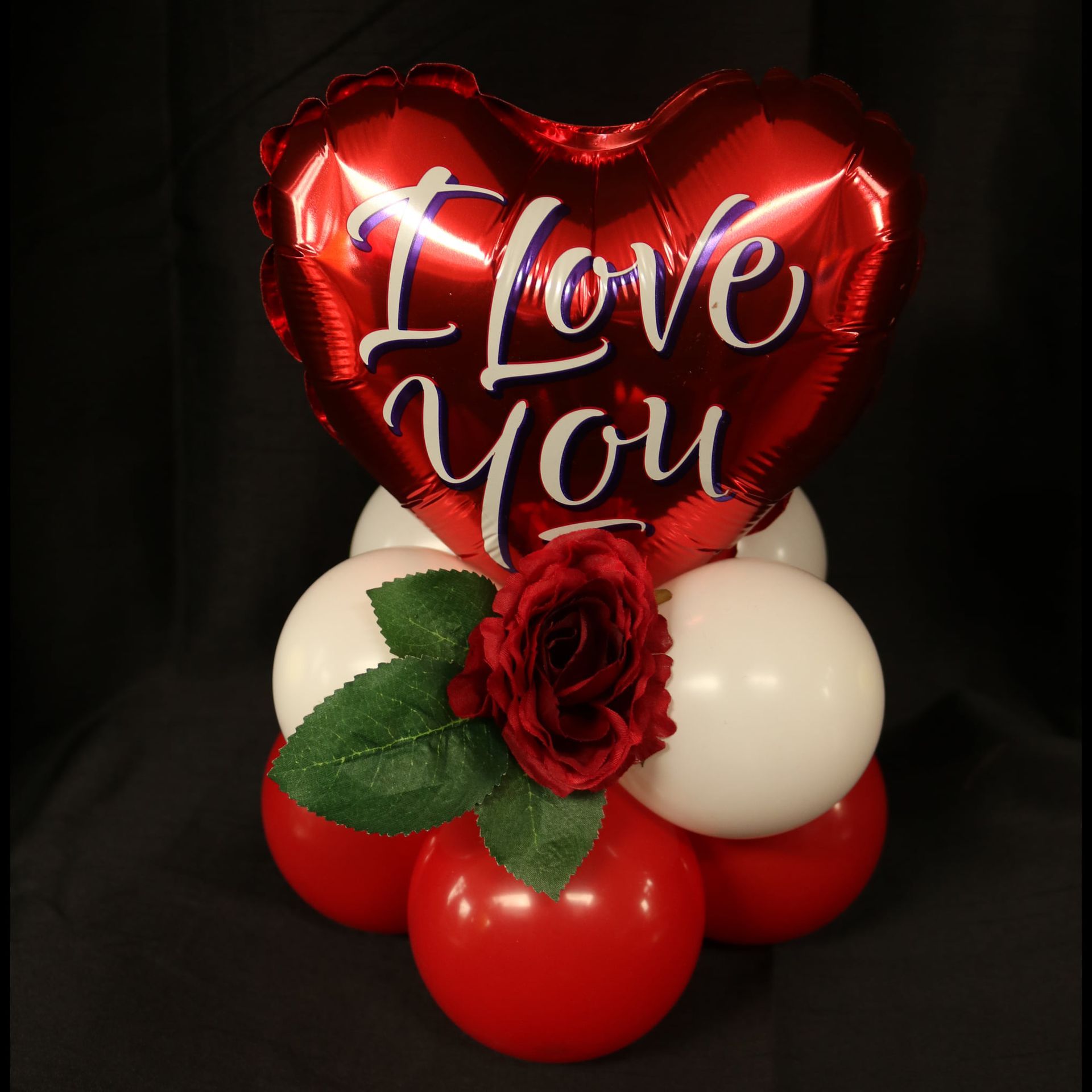 A red heart shaped balloon that says i love you