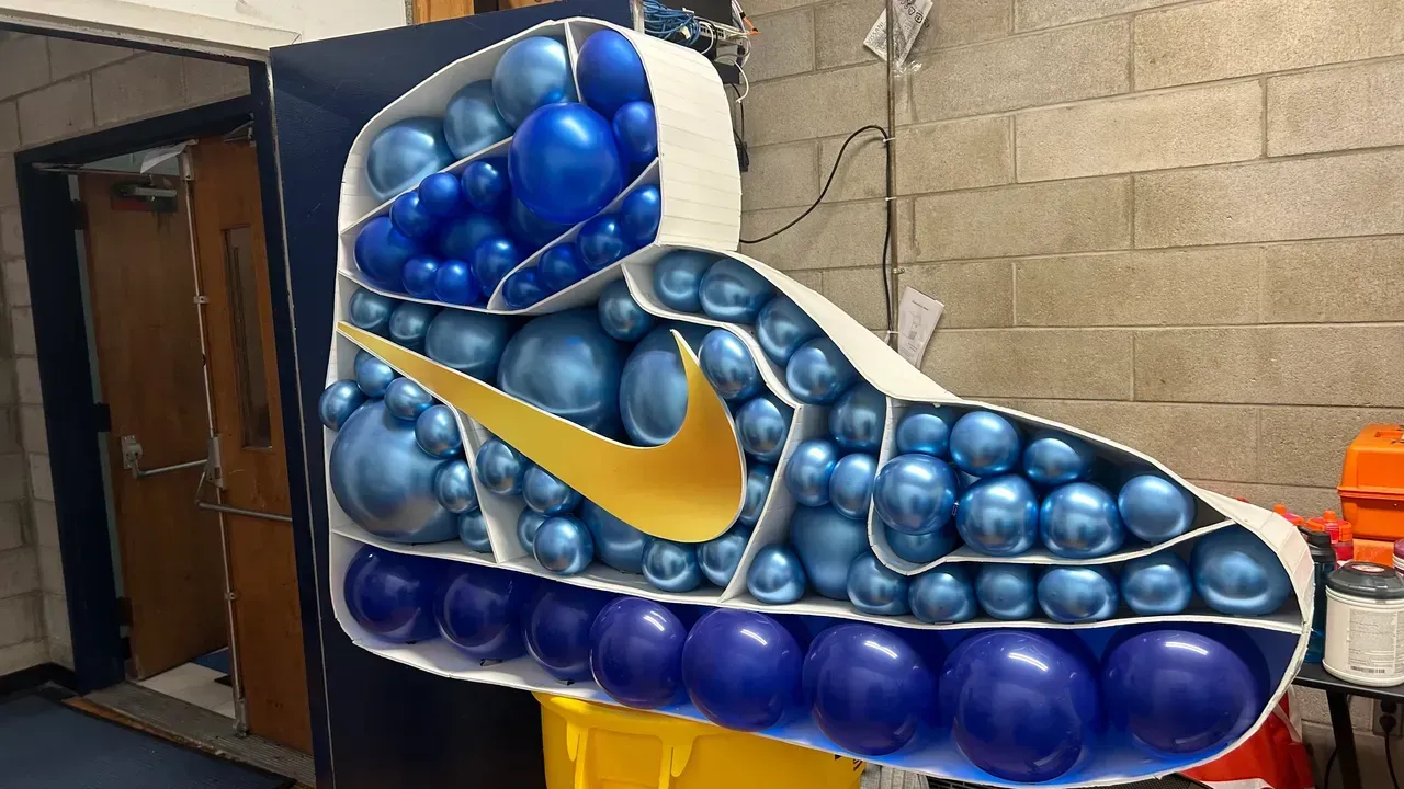 A nike shoe made out of blue and purple balloons.