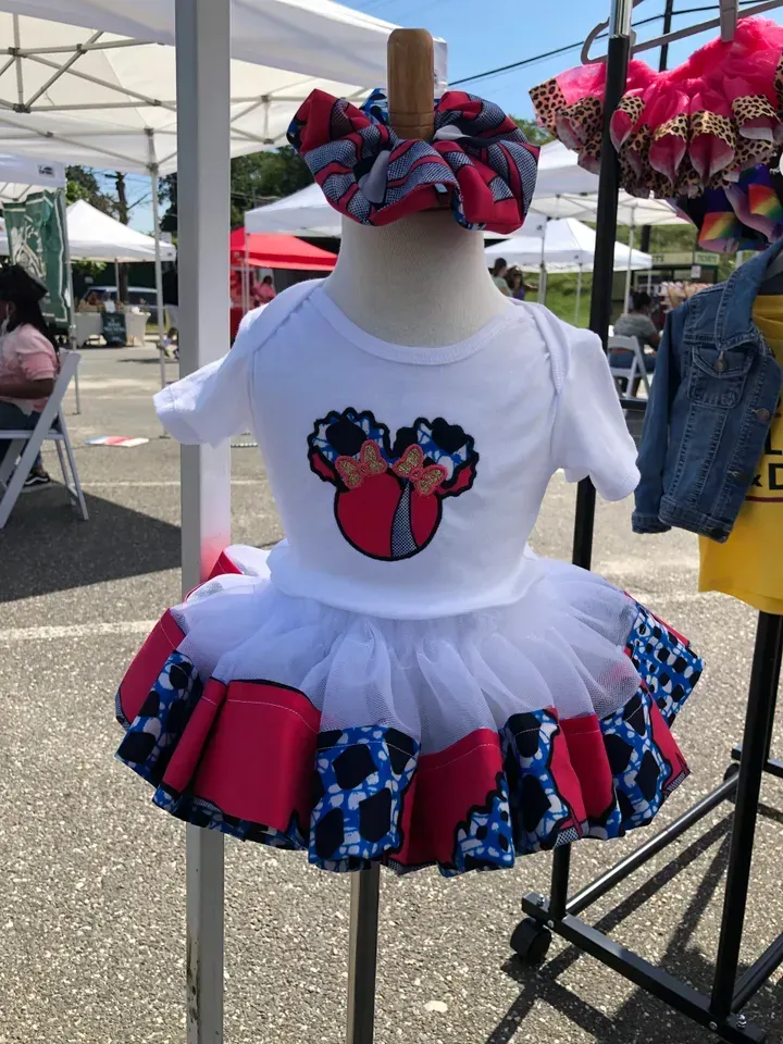 Baby outfit on mannequin, white top with mouse ears design, tutu skirt, and matching headband.